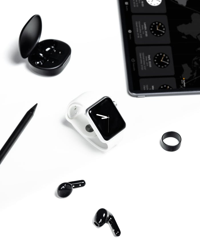 Stylish display of a modern workspace with gadgets like smartwatch, tablet, and headphones in a minimalist setting.